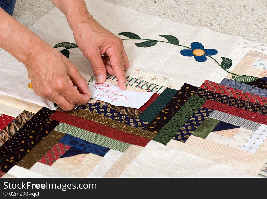 A woman pins a paper label on a section of material prior to final assembly. A woman pins a paper label on a section of material prior to final assembly.