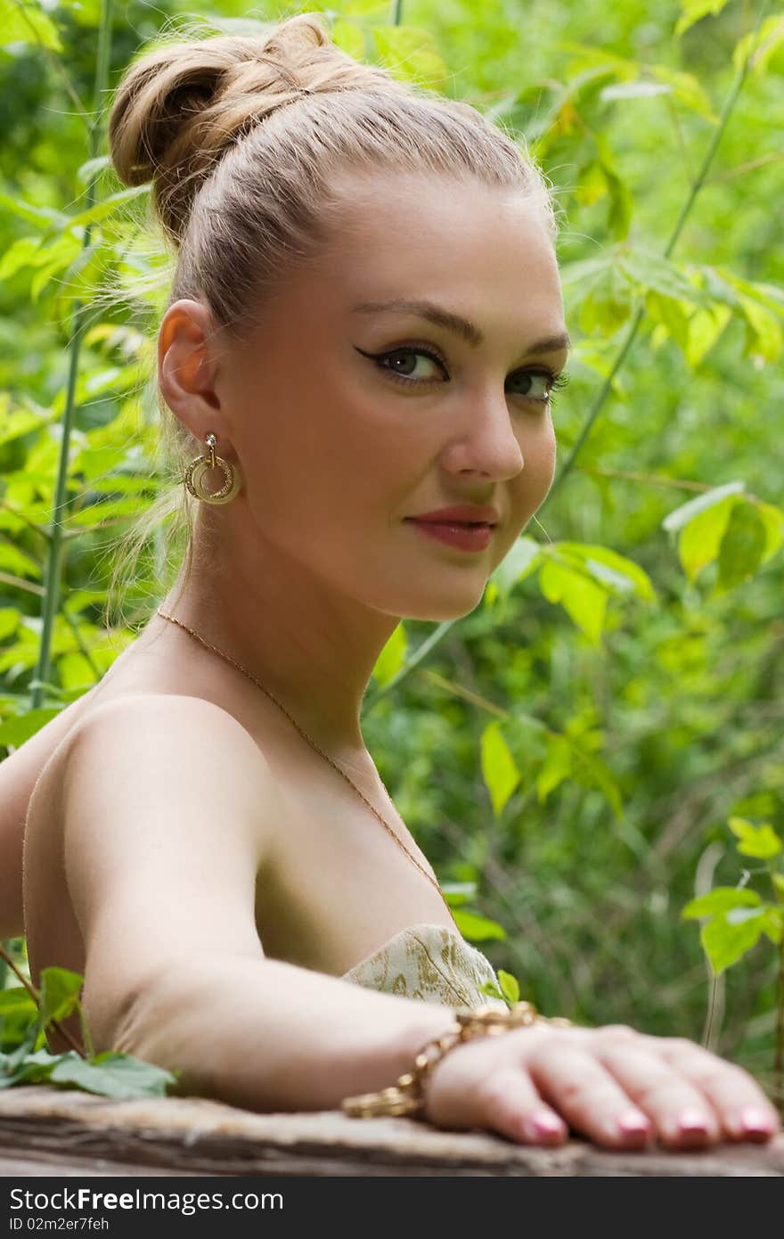 Attractive young lady posing somewhere on the green background outdoors. Attractive young lady posing somewhere on the green background outdoors