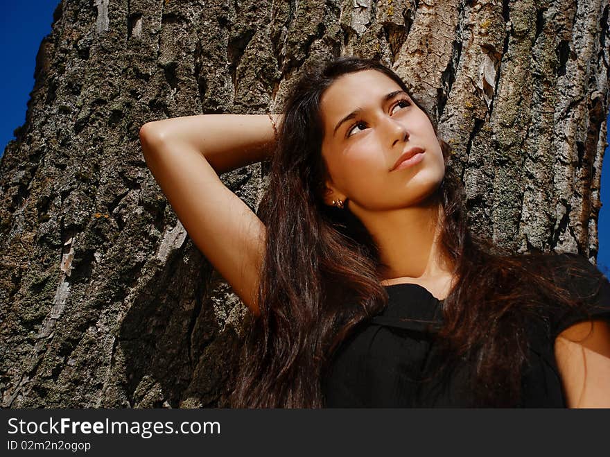 Close Up Of Beautiful Girl Next To A Tree.