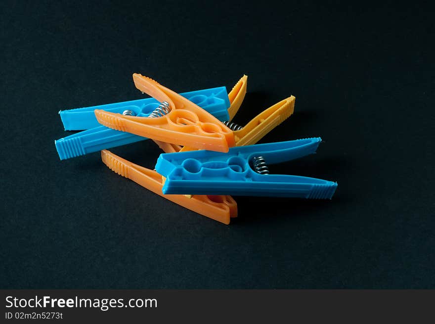 Different colored laundry clips on a black background.