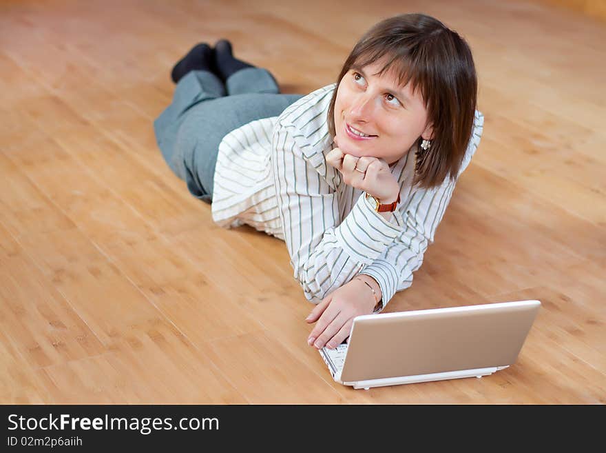 Beautiful business woman with a white laptop on floor dreaming. Beautiful business woman with a white laptop on floor dreaming