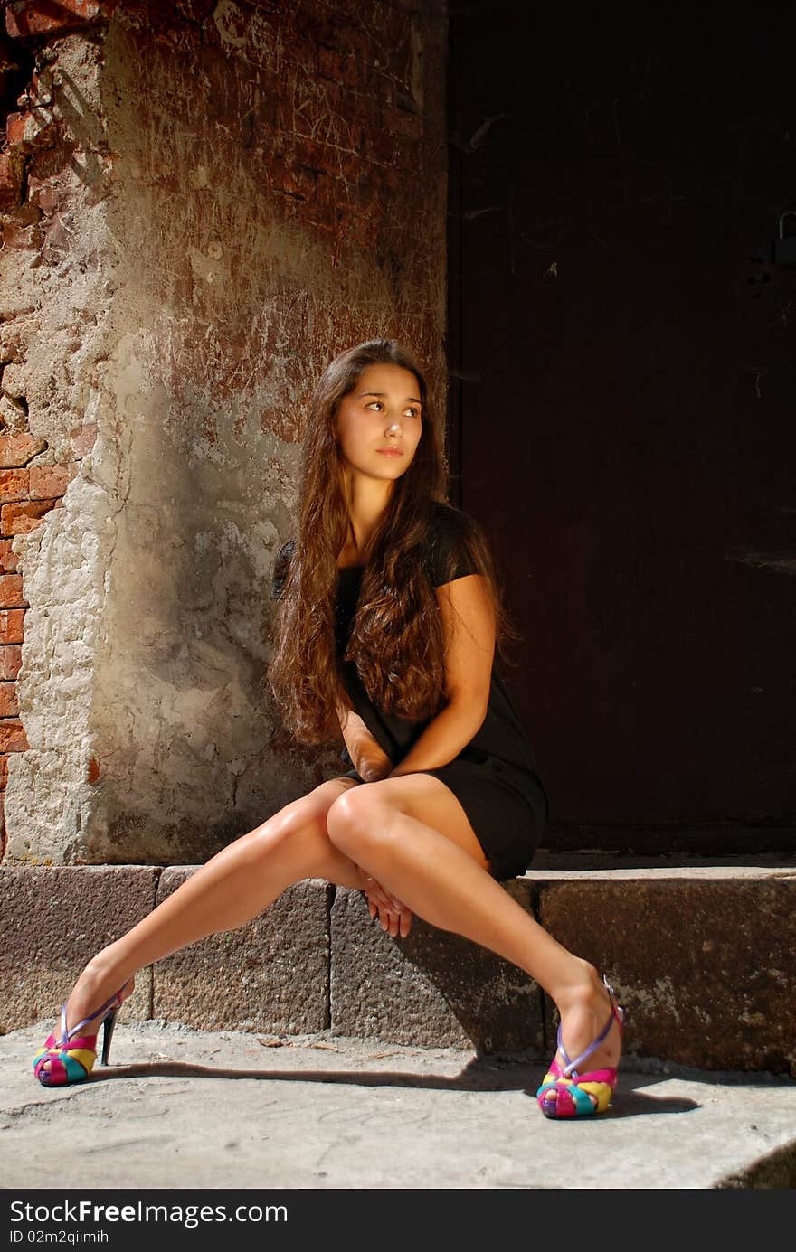 Charming lady in black sitting on staircase.