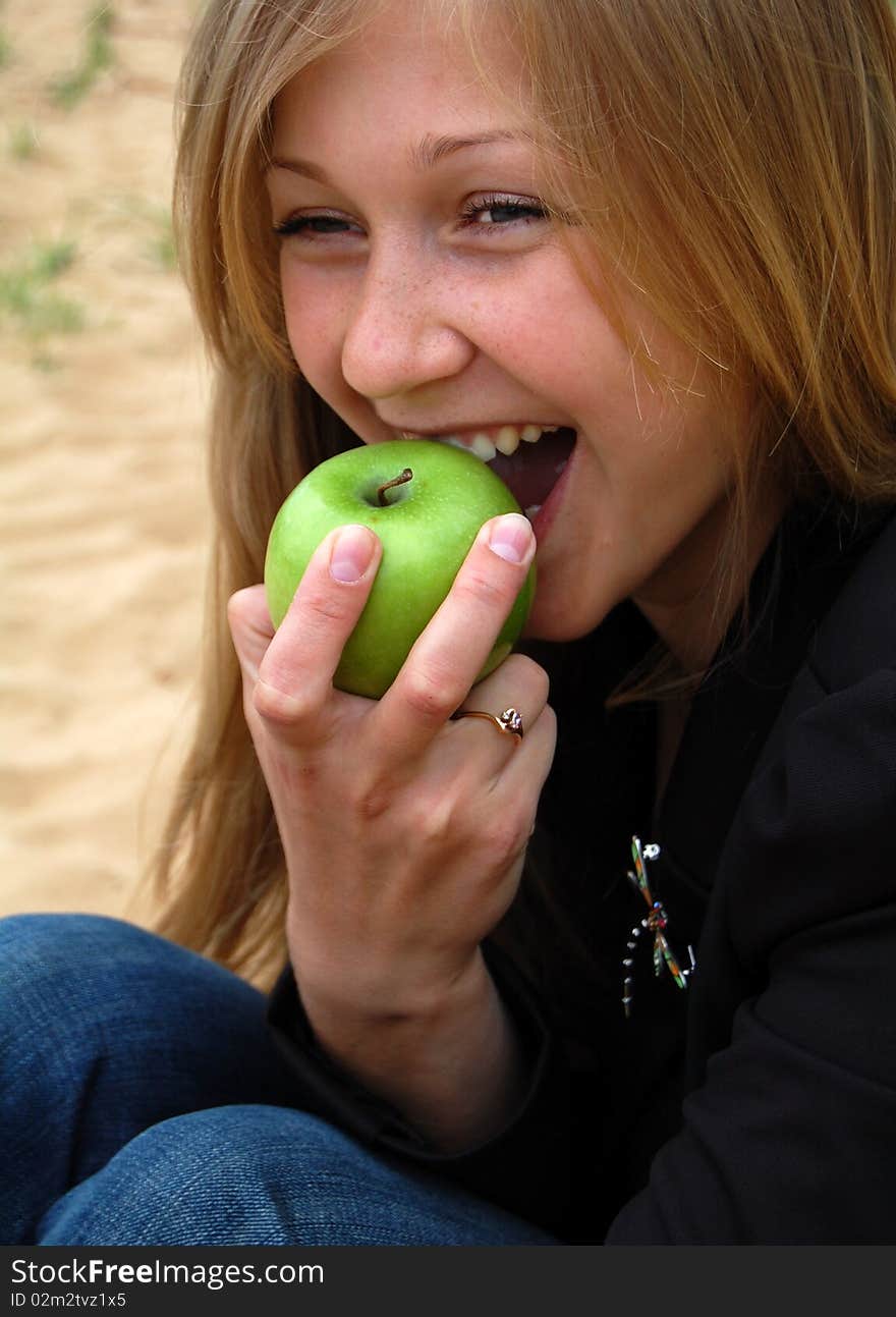 Beautiful happy blond woman bite off green apple