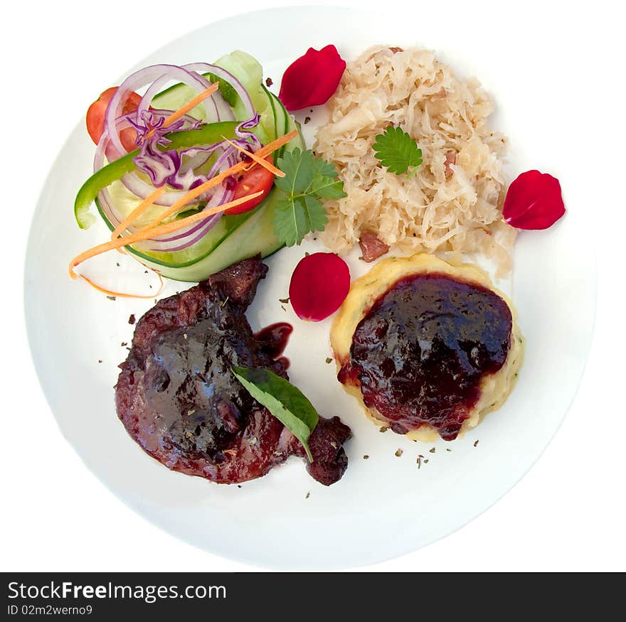 Pork cutlet served with sauerkraut, mash, salad and cranberry sauce garnished with rose petals on white background. Pork cutlet served with sauerkraut, mash, salad and cranberry sauce garnished with rose petals on white background