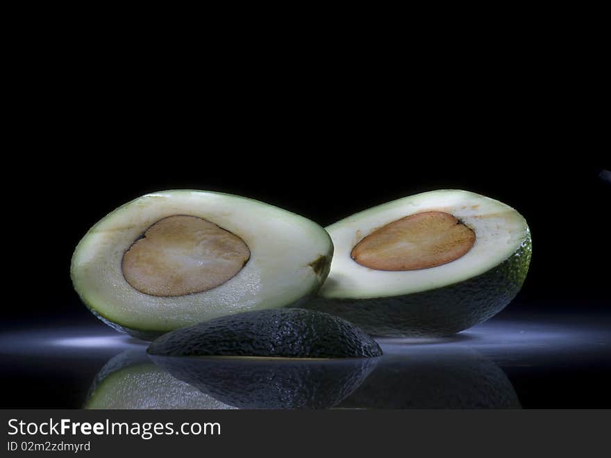 Two slices of avocado on a dark background