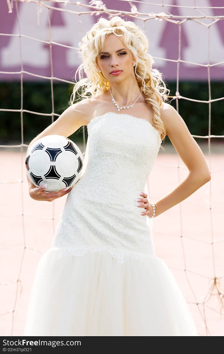 Young beautiful bride standing on the gate with ball. Young beautiful bride standing on the gate with ball