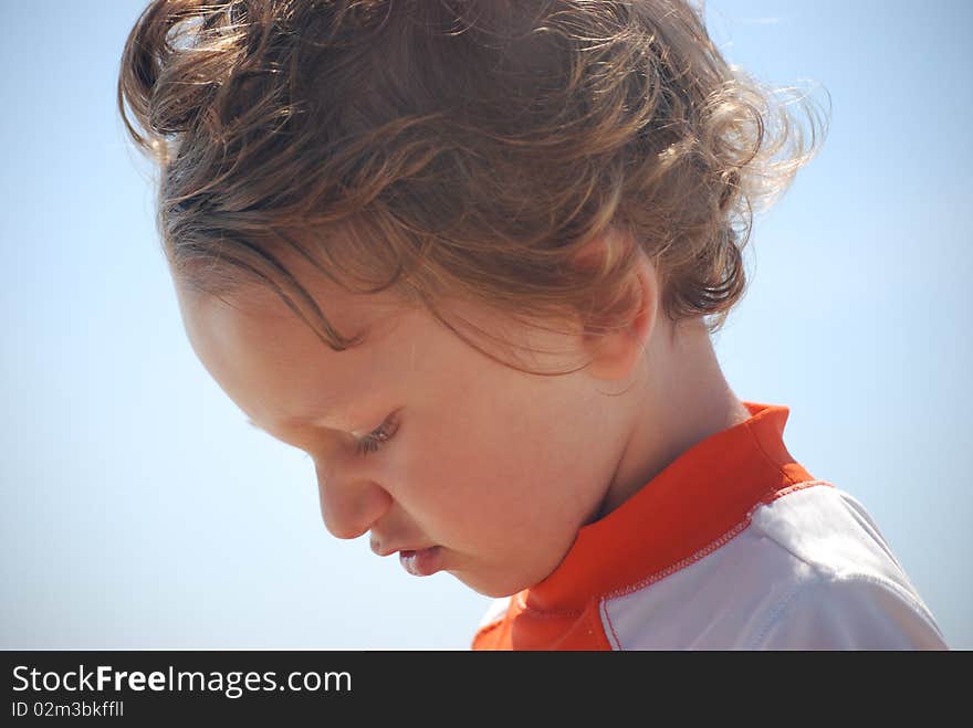 A side profile of a white caucasian toddler boy that is outside with the blue sky in the background. A side profile of a white caucasian toddler boy that is outside with the blue sky in the background.