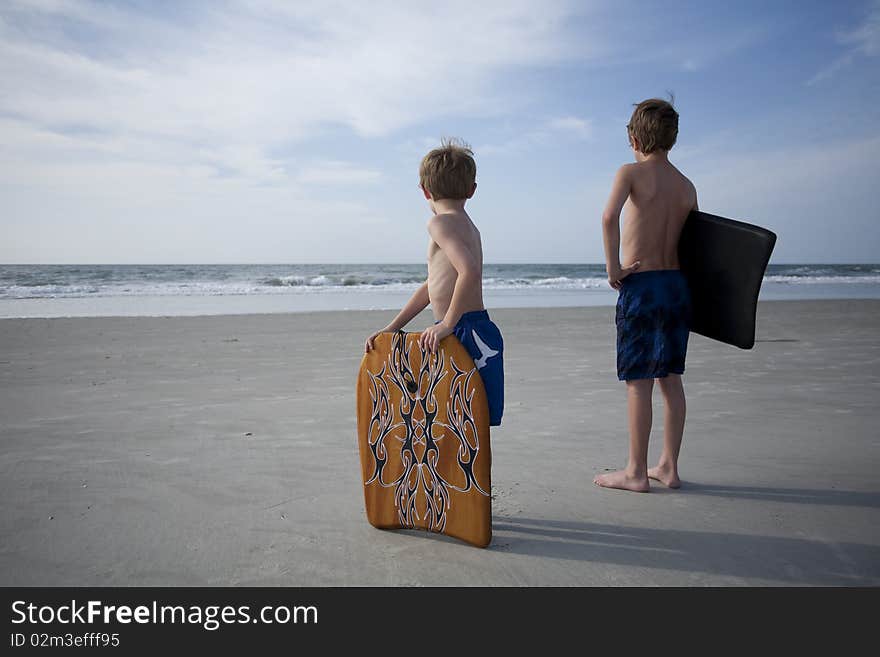 Two young boys at the beach with boogie boards