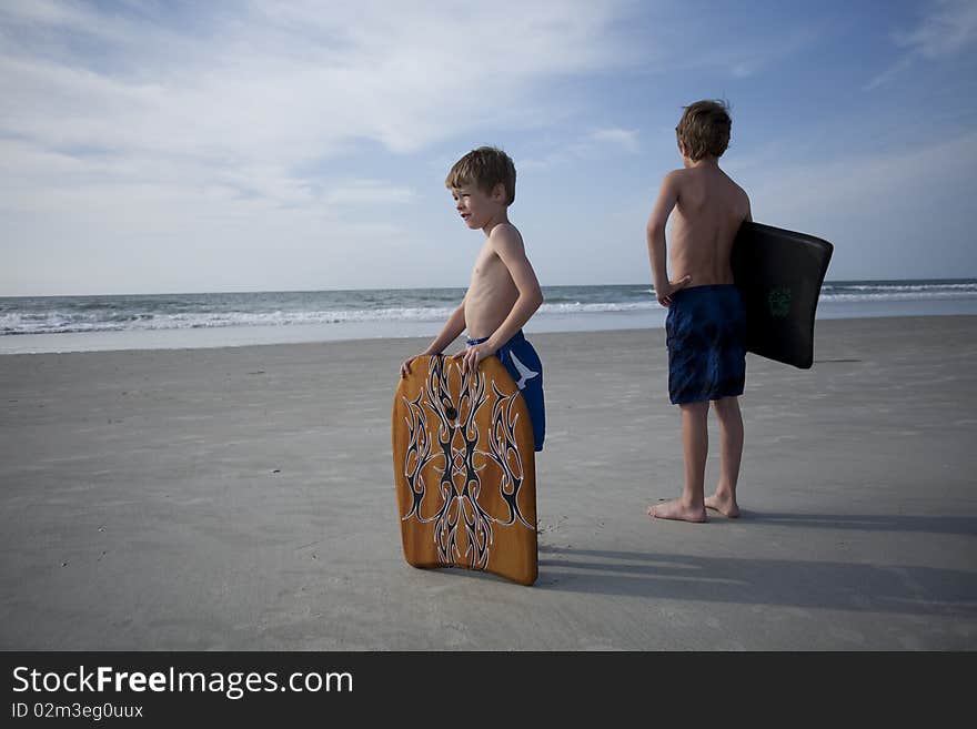 Two young boys at the beach with boogie boards