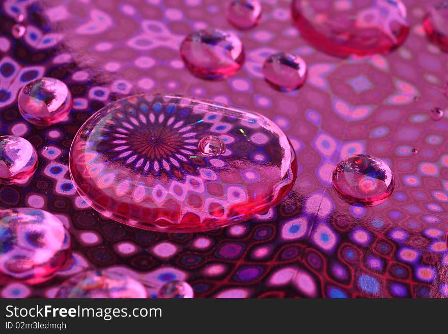 Macro image of water drops on a pink foil patterned backdrop. Macro image of water drops on a pink foil patterned backdrop