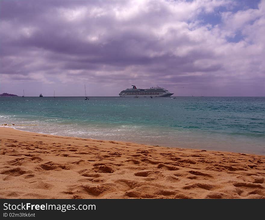 Cruise ship making its way to the harbor passing in front of the beach. Dramatic cloudy sky with small patches of sun giving the ocean a beautiful green color. Cruise ship making its way to the harbor passing in front of the beach. Dramatic cloudy sky with small patches of sun giving the ocean a beautiful green color