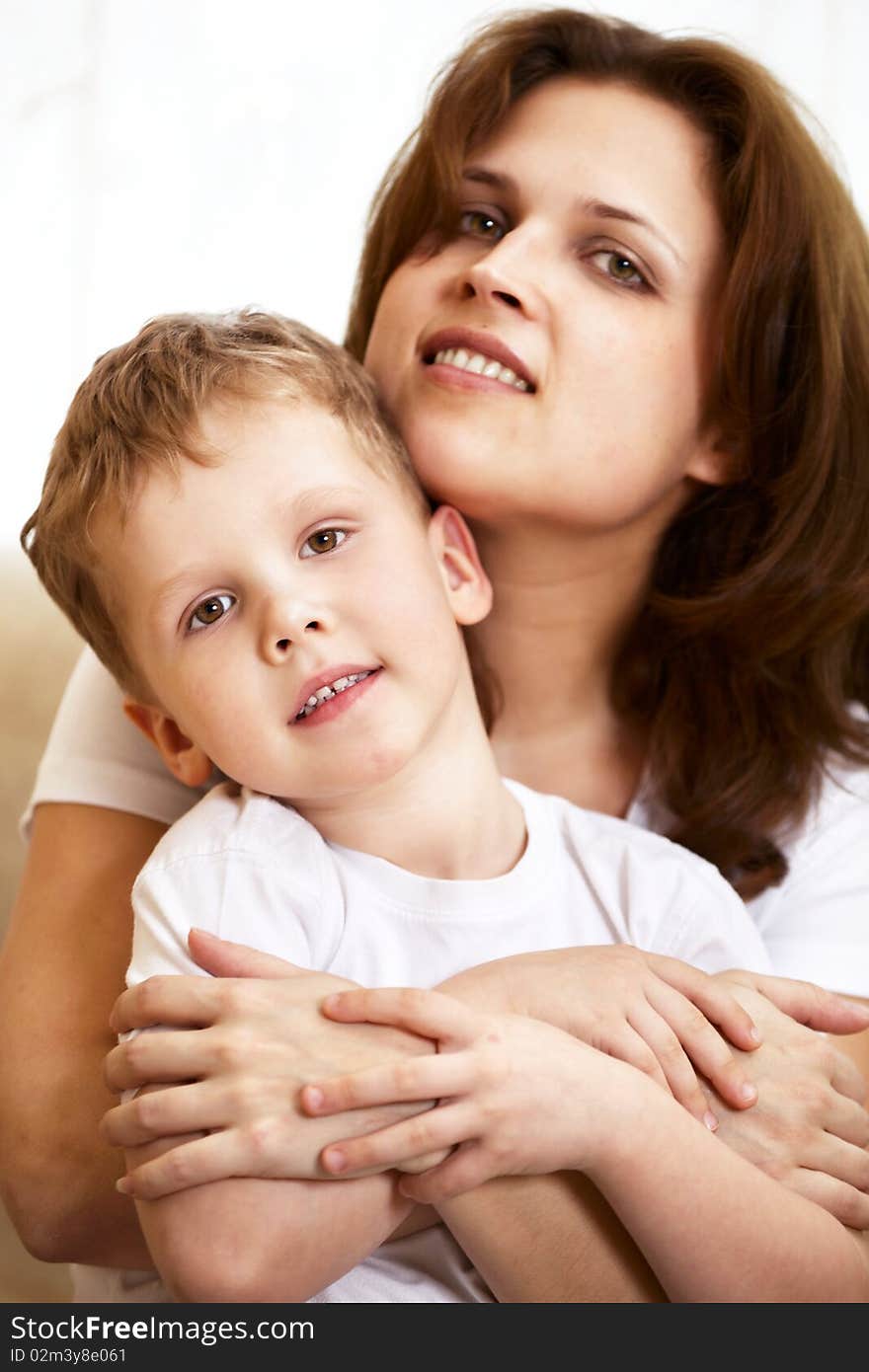 Happy young mother hugging her little son indoor; shallow DOF, focus on boys eyes