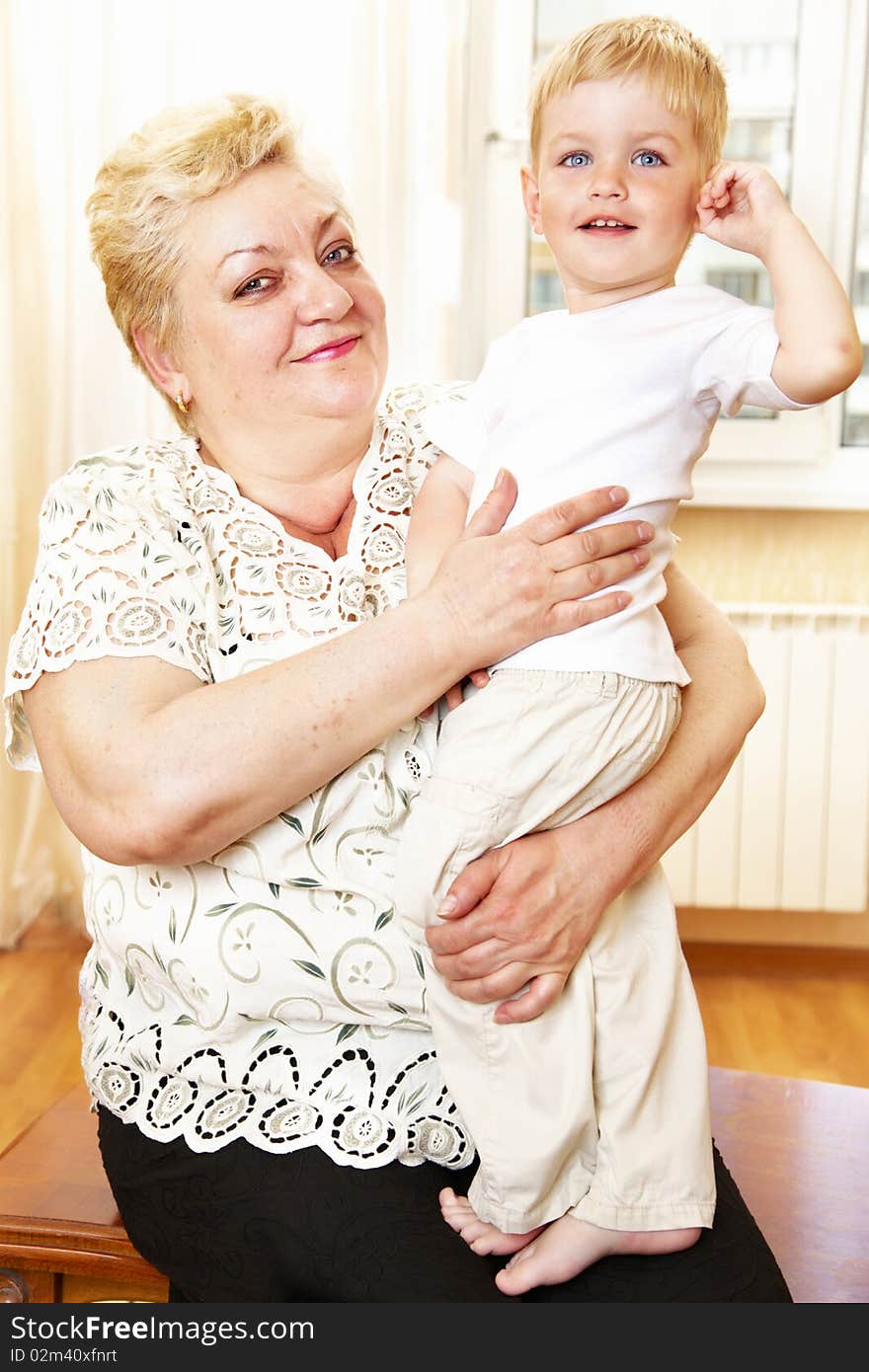 Grandmother holding her grandson indoor; shallow DOF, focus on womans closest eye. Grandmother holding her grandson indoor; shallow DOF, focus on womans closest eye