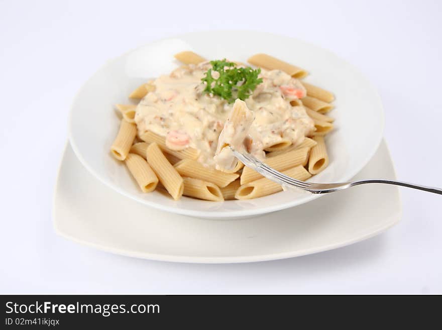 Penne with white sauce on a plate decorated with parsley some of it on a fork