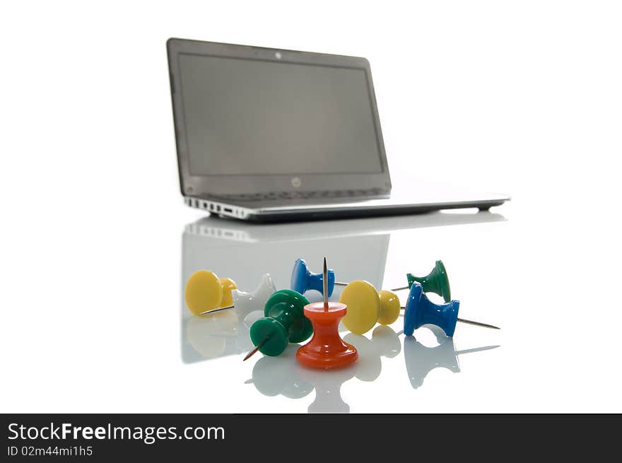 Several many-coloured thumbtacks and laptop over white background. Several many-coloured thumbtacks and laptop over white background