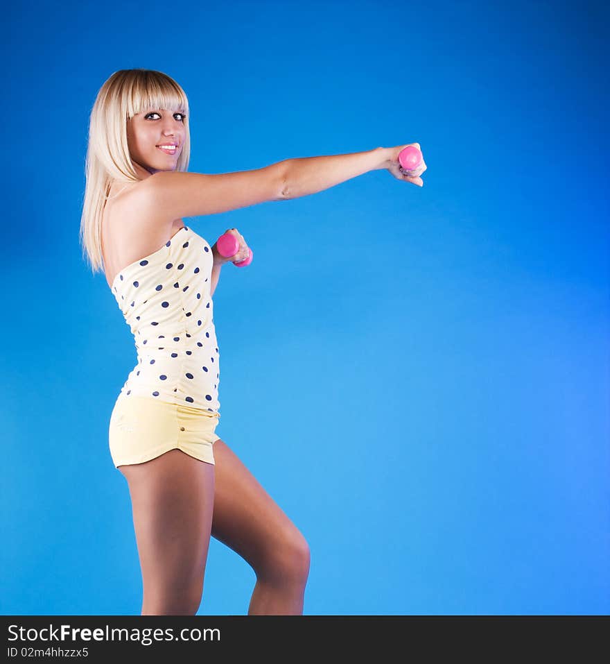 Blonde female working out with pink dumbbells