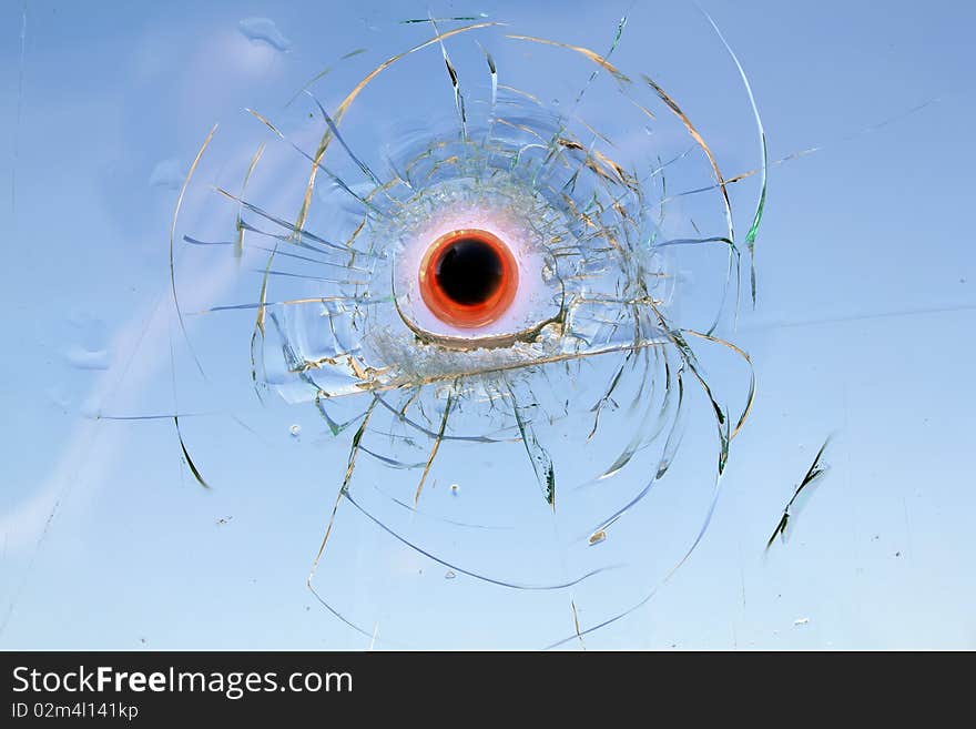 The heated steel bullet has got stuck in the broken automobile glass. The heated steel bullet has got stuck in the broken automobile glass