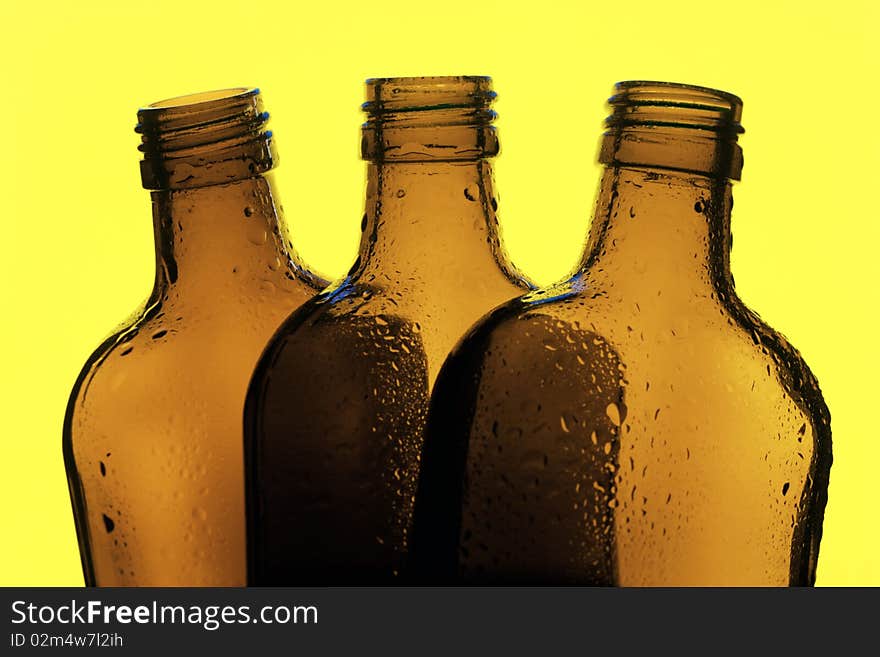 Three glass bottles on a yellow background. Three glass bottles on a yellow background