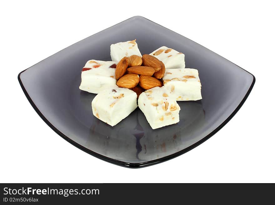 Delicious nougat on black glass plate, isolated on white