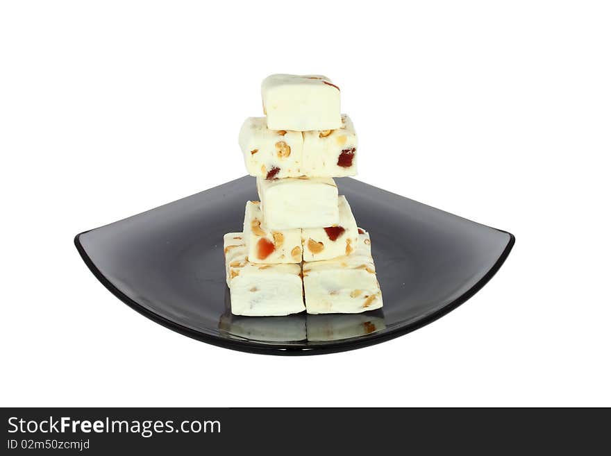 Delicious nougat on black glass plate, isolated on white