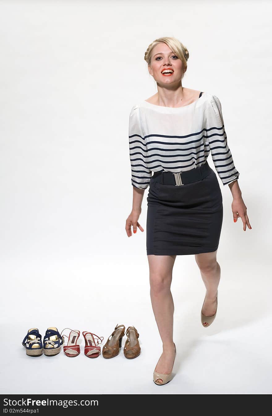 Young blond posing alongside 3 pairs of shoes. Young blond posing alongside 3 pairs of shoes