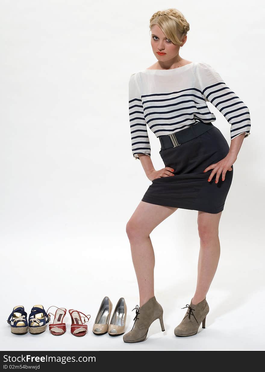 Young blond posing alongside 3 pairs of shoes. Young blond posing alongside 3 pairs of shoes