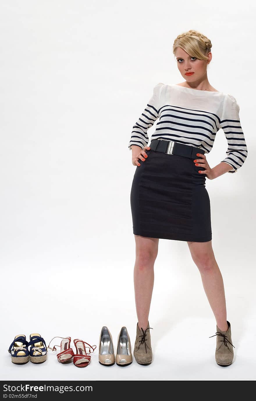 Young blond posing alongside 3 pairs of shoes. Young blond posing alongside 3 pairs of shoes