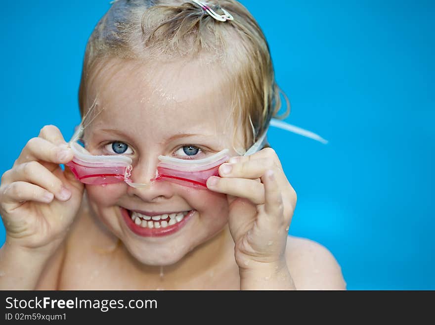 Young pretty girl in swimming-pool holding googles