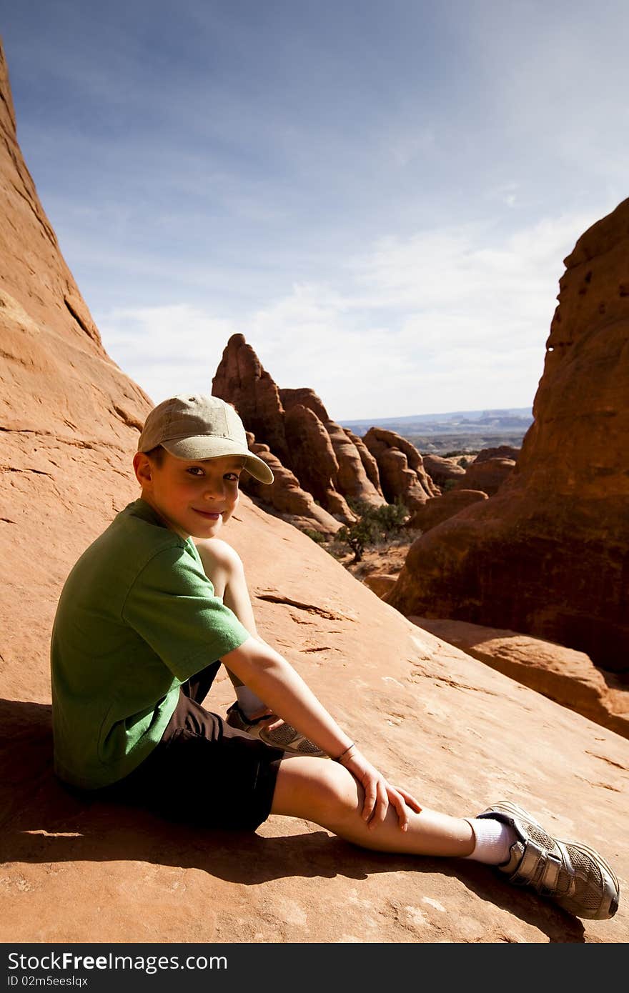 Young boy sitting for a rest while hiking in Arches National Park near Moab UT