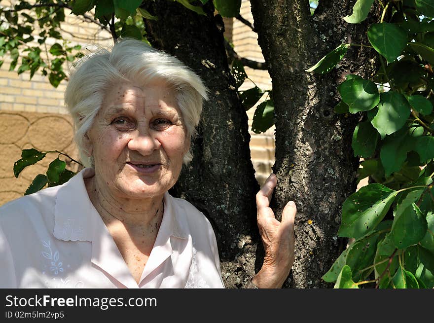 Mature woman standing in a garden near the house. Mature woman standing in a garden near the house