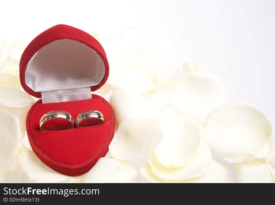 Matching rings in a heart shapped valvet box and in white background with white rose petals. Matching rings in a heart shapped valvet box and in white background with white rose petals