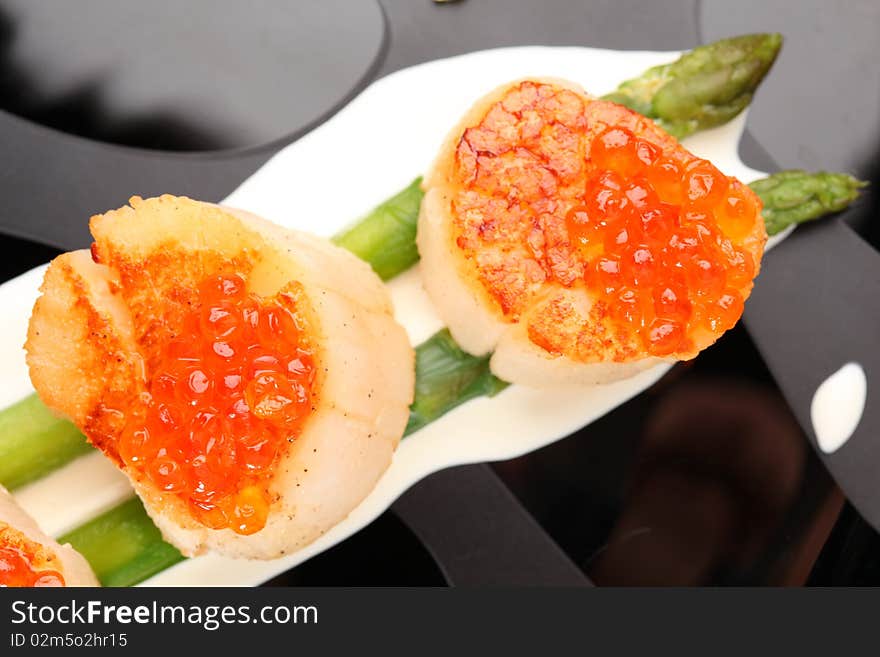 Grilled sea scallops with asparagus in a black plate