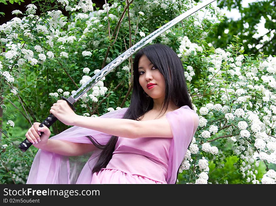 Beutiful japanese woman in pink dress wields a sword