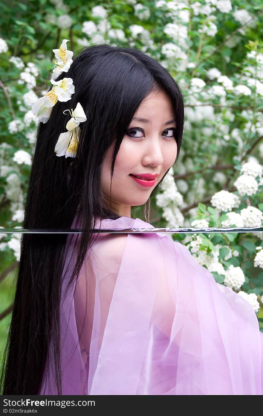 Beutiful japanese woman in pink dress wields a sword