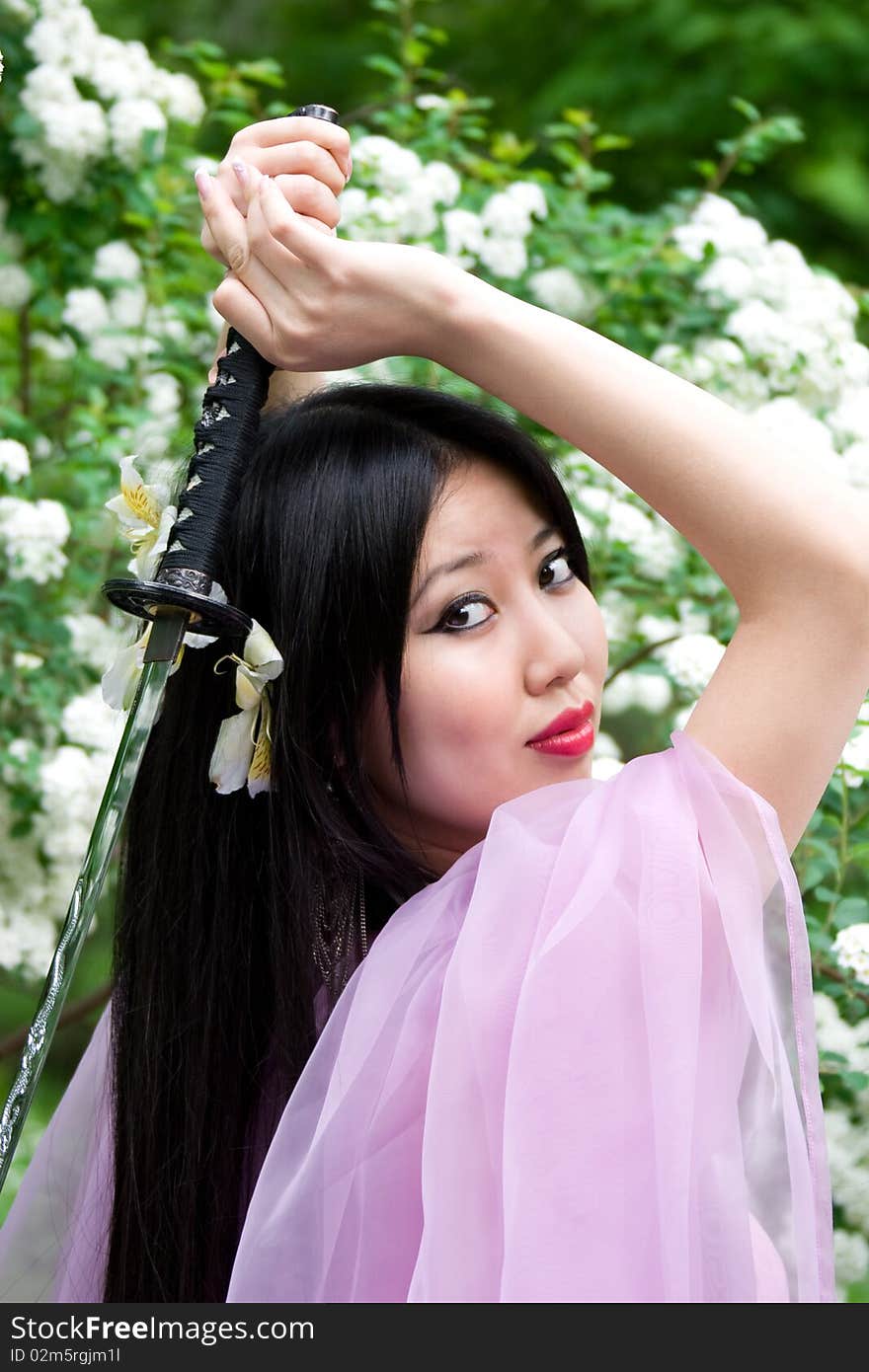 Beutiful japanese woman in pink dress wields a sword