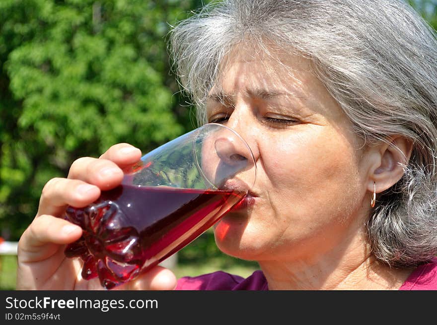 Middle-aged woman with pleasure drinking cherry juice. Middle-aged woman with pleasure drinking cherry juice