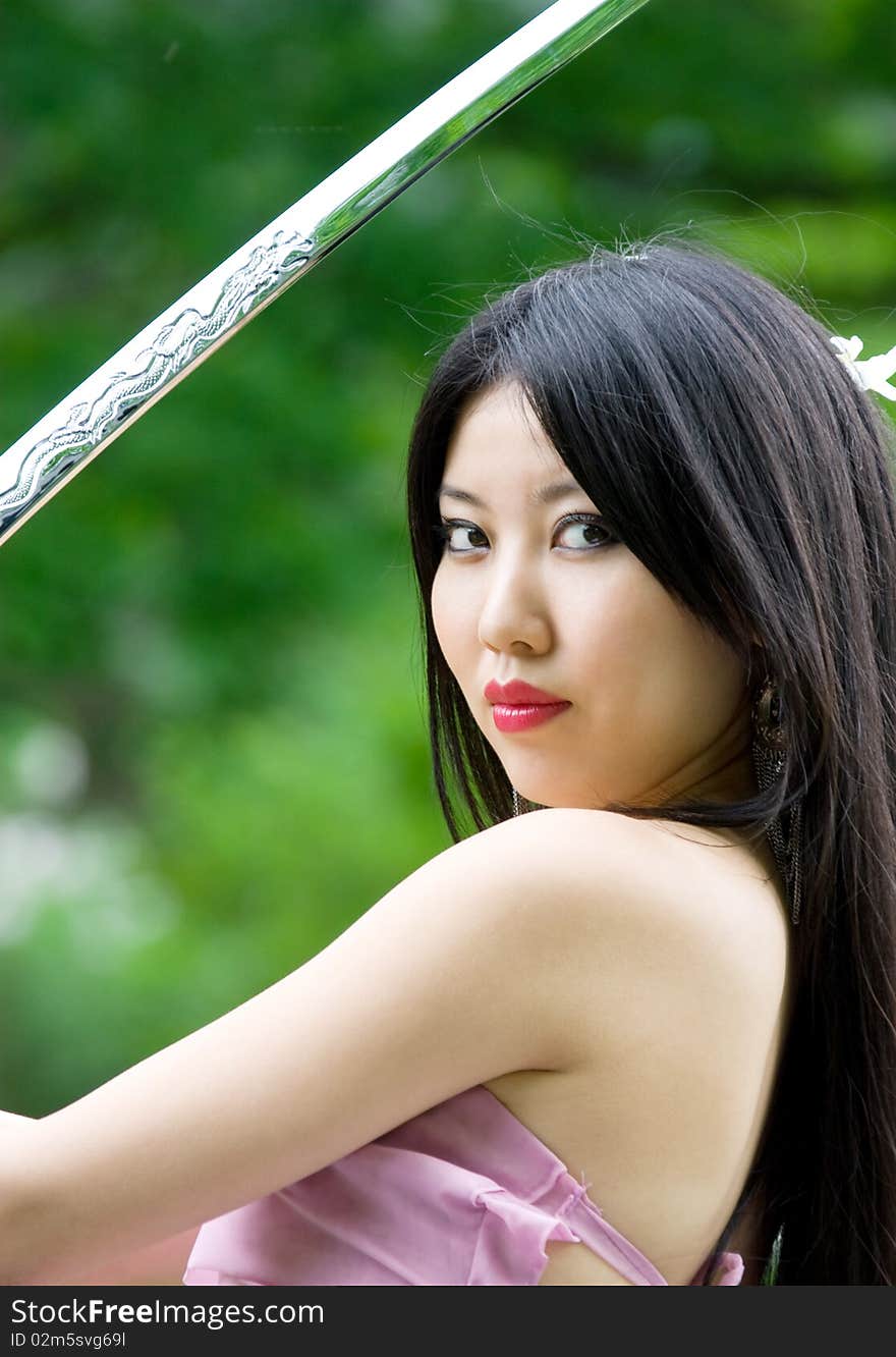 Beutiful japanese woman in pink dress wields a sword