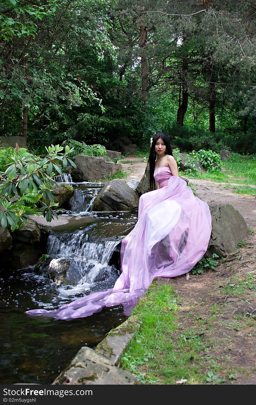 Beautiful Japanese woman in a pink dress sitting on a stone. Beautiful Japanese woman in a pink dress sitting on a stone