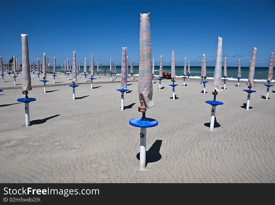 Folded umbrellas on a beach in Italy