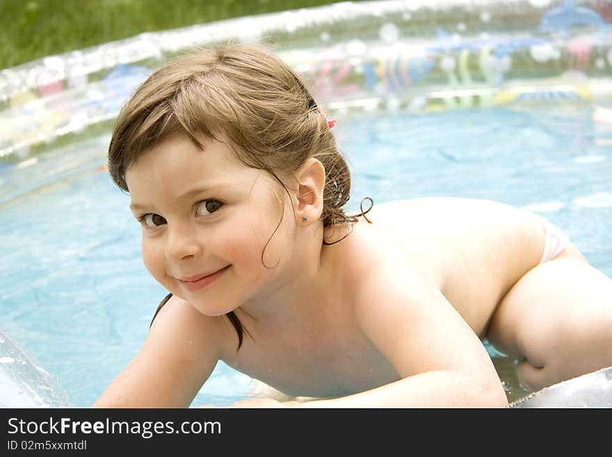 The beautiful girl artfully looks a summer sunny day from pool. The beautiful girl artfully looks a summer sunny day from pool