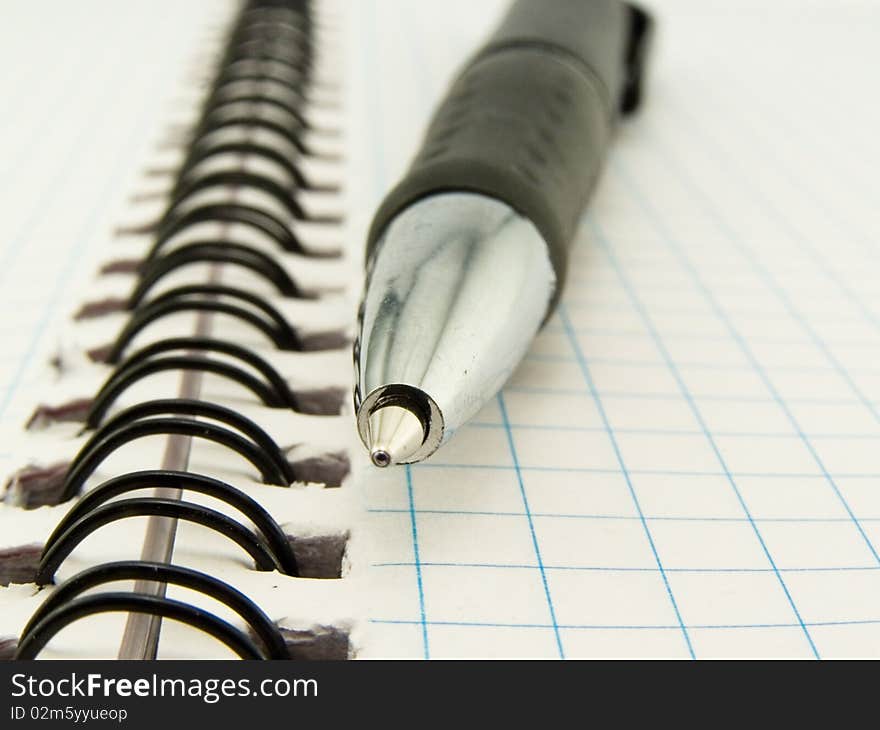 Ball-point pen rests upon clean notebook in check. Ball-point pen rests upon clean notebook in check