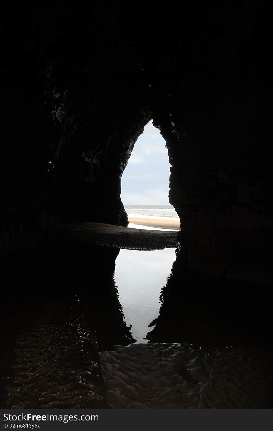 A view from the inside of a beach cave looking out at the sea. A view from the inside of a beach cave looking out at the sea