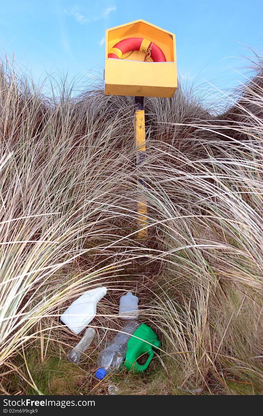 Lifebuoy among wild grass and plastic rubbish