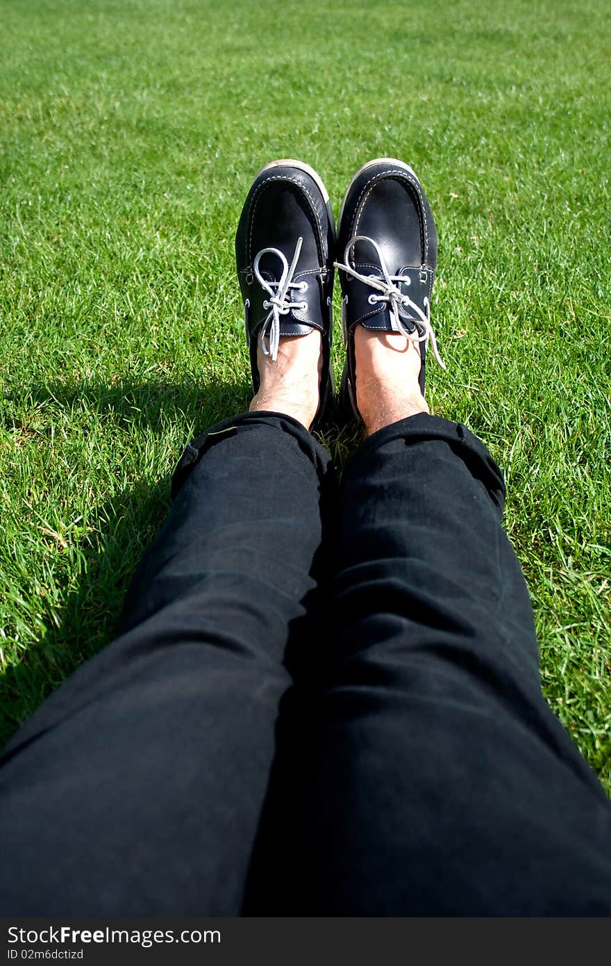 Blue leather shoes at the end of long male legs on a grass background. Blue leather shoes at the end of long male legs on a grass background.