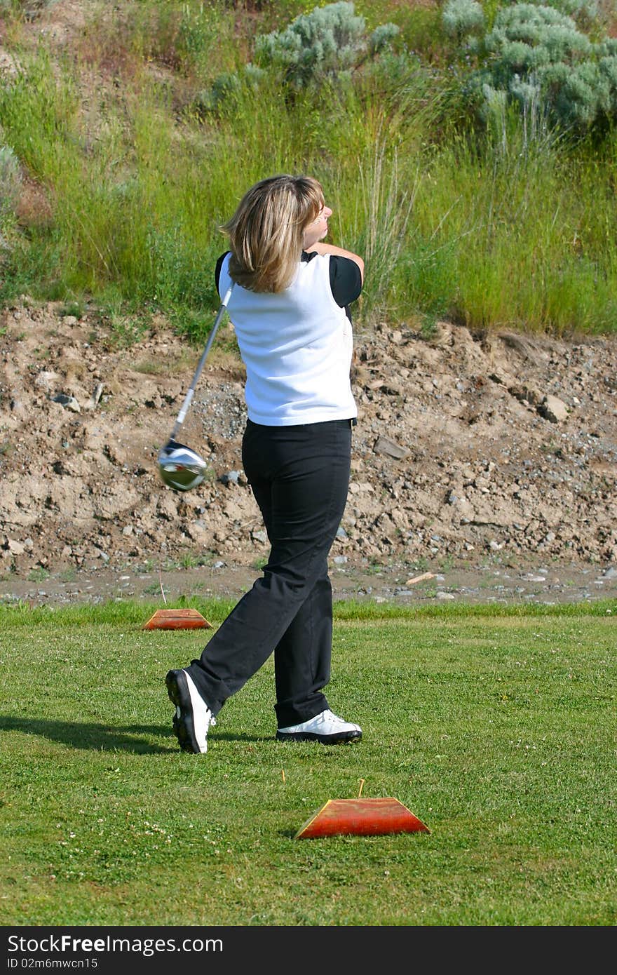 Blond female golfer on the tee-box with a driver