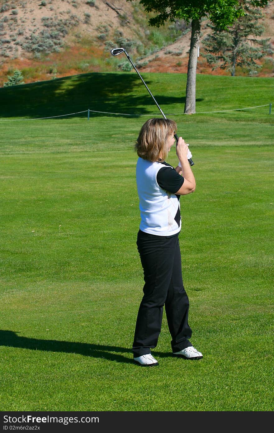 Blond female golfer following her golf shot