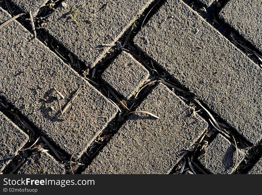 Old Brick pattern in zigzag design with grass growing in between the cracks