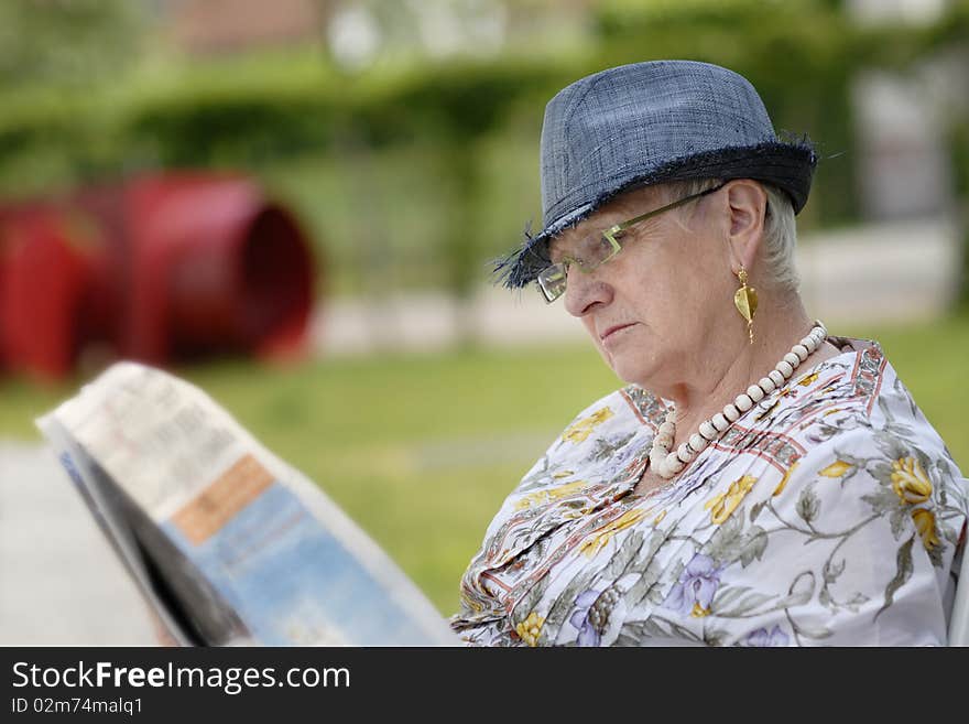 Senior woman reading a newspaper in the garden