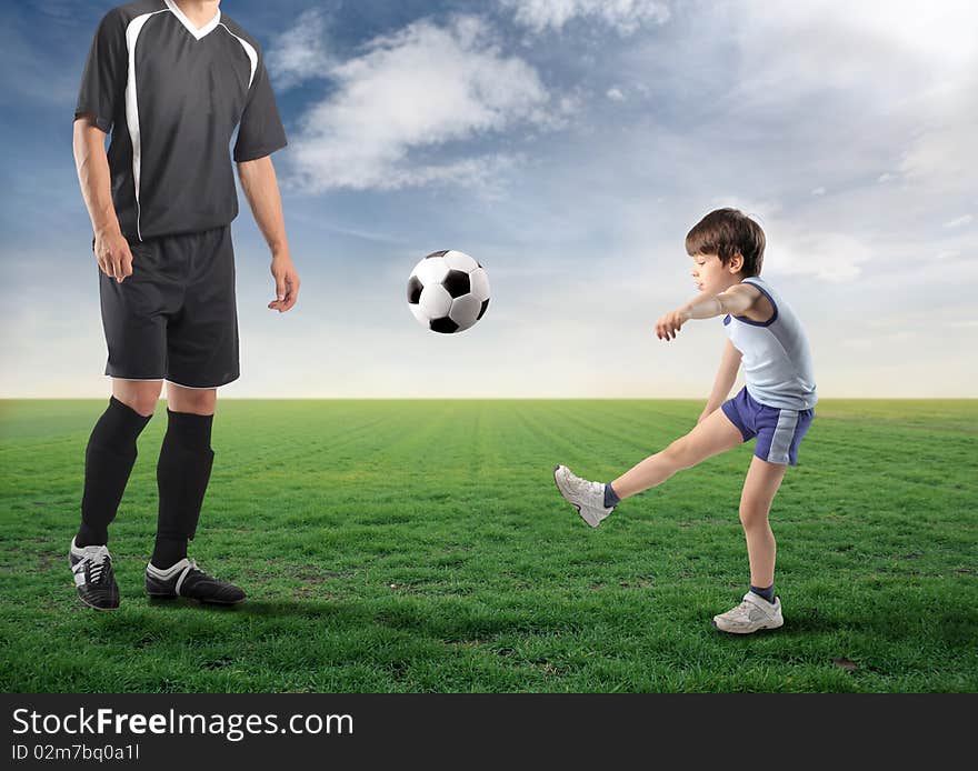 Child kicking a ball and older football player next to him. Child kicking a ball and older football player next to him