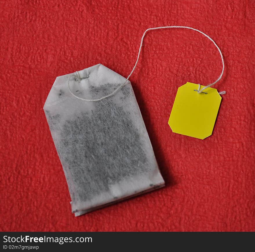 Yellow labeled teabag on red background